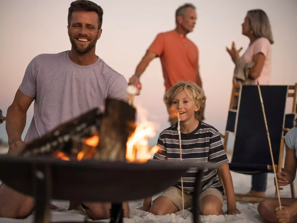 A family roasting s'mores over a bonfire on at Grayton Beach.
