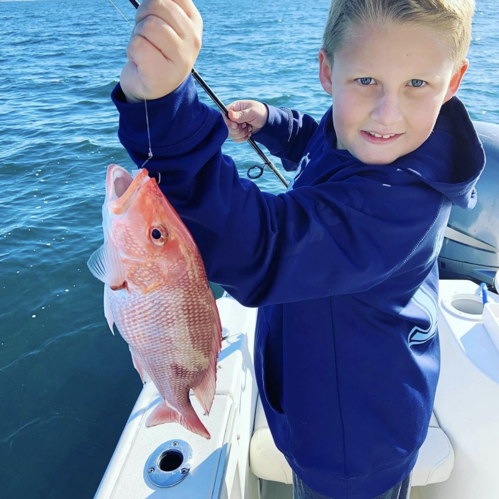 A boy with a freshly caught redfish. Courtesy of Blue Sky Fishing 30A.