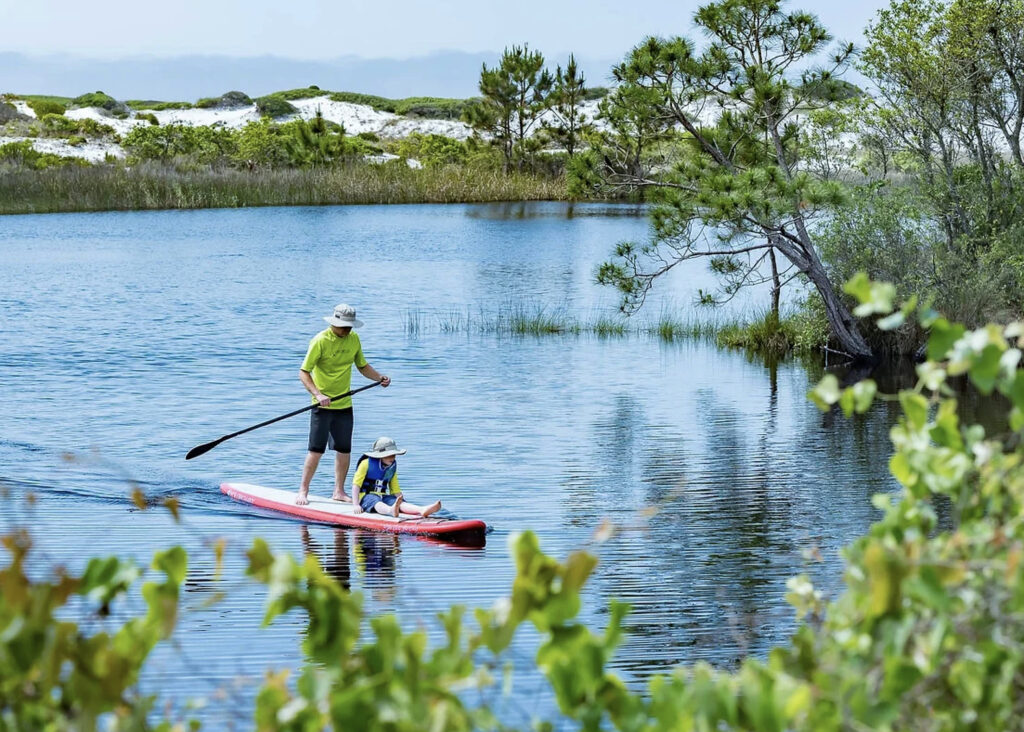 Man and son paddleboarding along 30A.