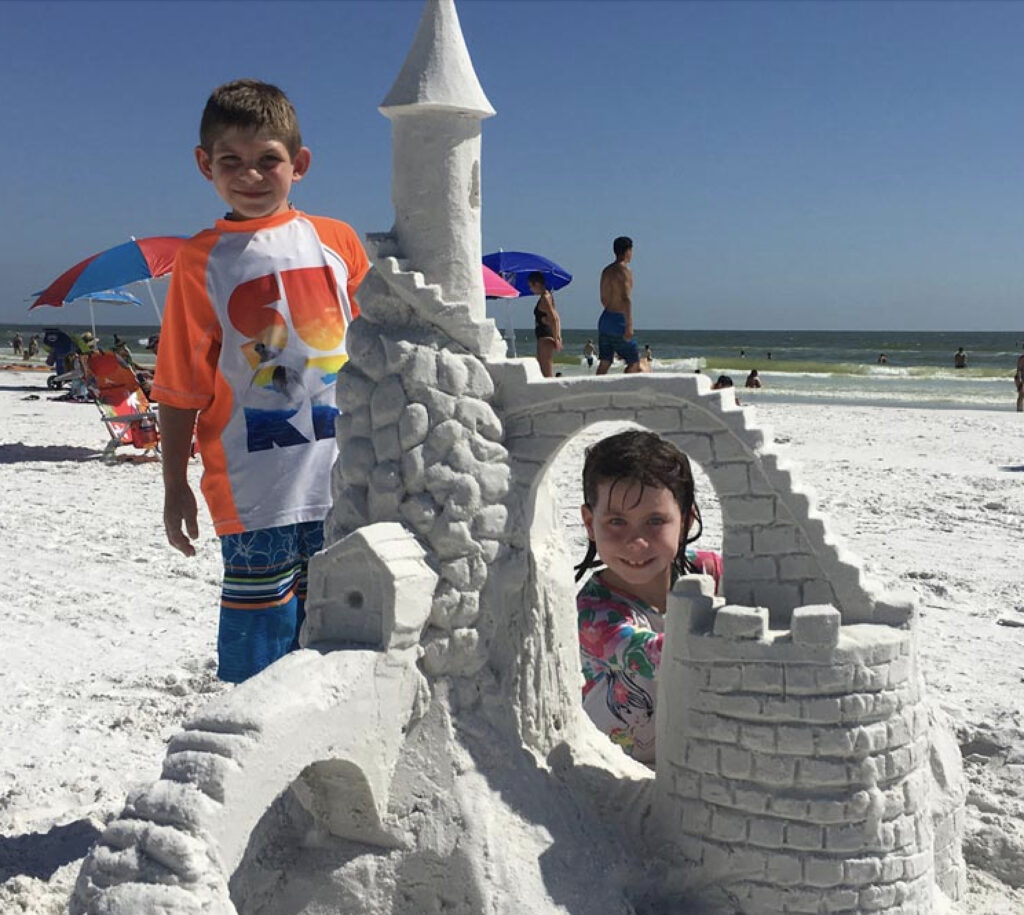 Kids pose with their epic sandcastle, thanks to 30A's Beach Sand Sculptures. 