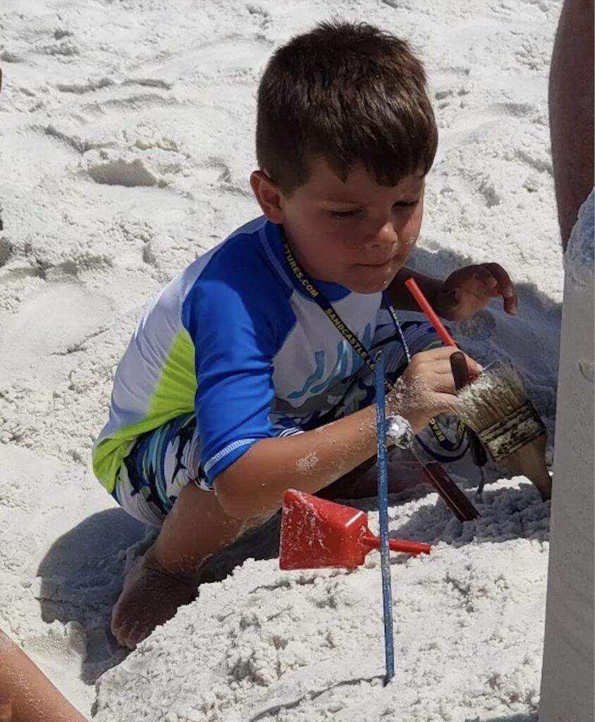 Kid building an epic sandcastle, thanks to 30A's Beach Sand Sculptures.